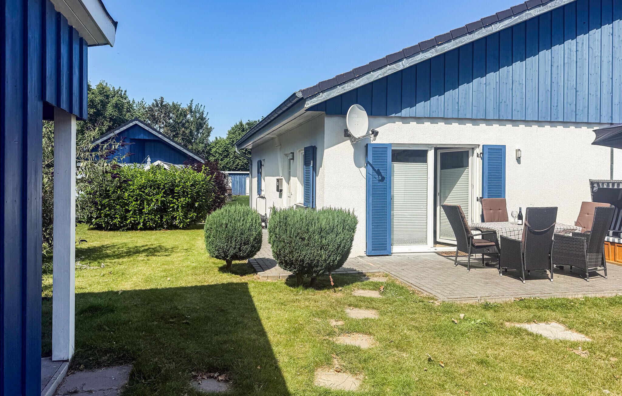 A residential property with a patio area, outdoor furniture, and a well-maintained lawn.