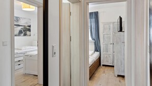 A narrow hallway leading to a bedroom with a bed, a wardrobe, and a bathroom with a toilet and sink. - Ferienhaus 31 Altefähr (Altefähr/Rügen)