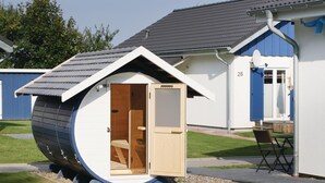 A small, single-room house with a sloped roof and a door that opens to a wooden interior. - Ferienhaus 31 Altefähr (Altefähr/Rügen)