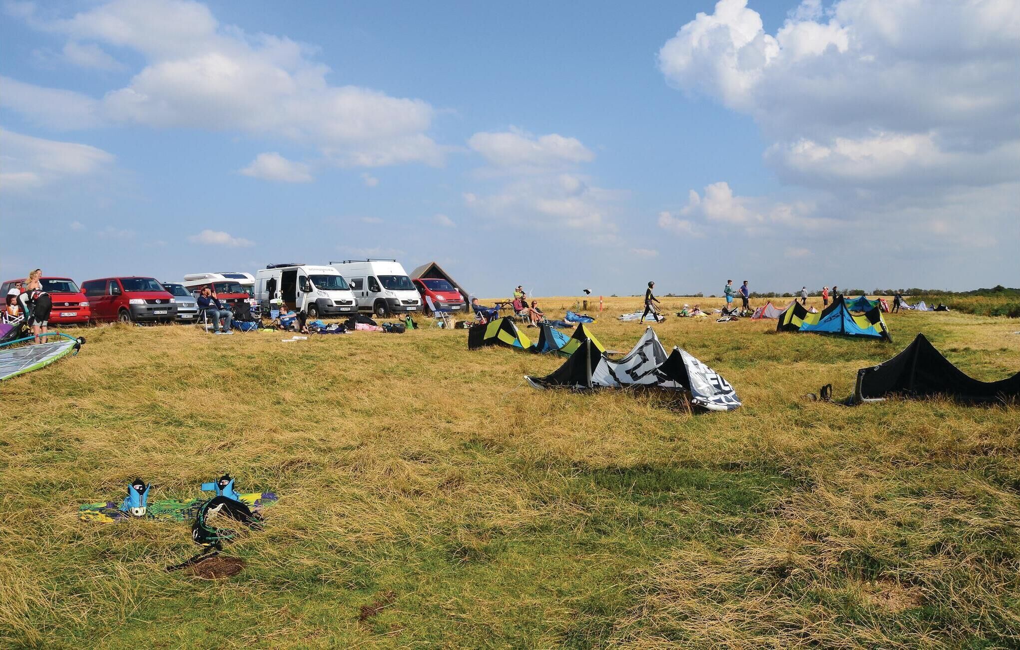 A campsite with tents, vehicles, and people.