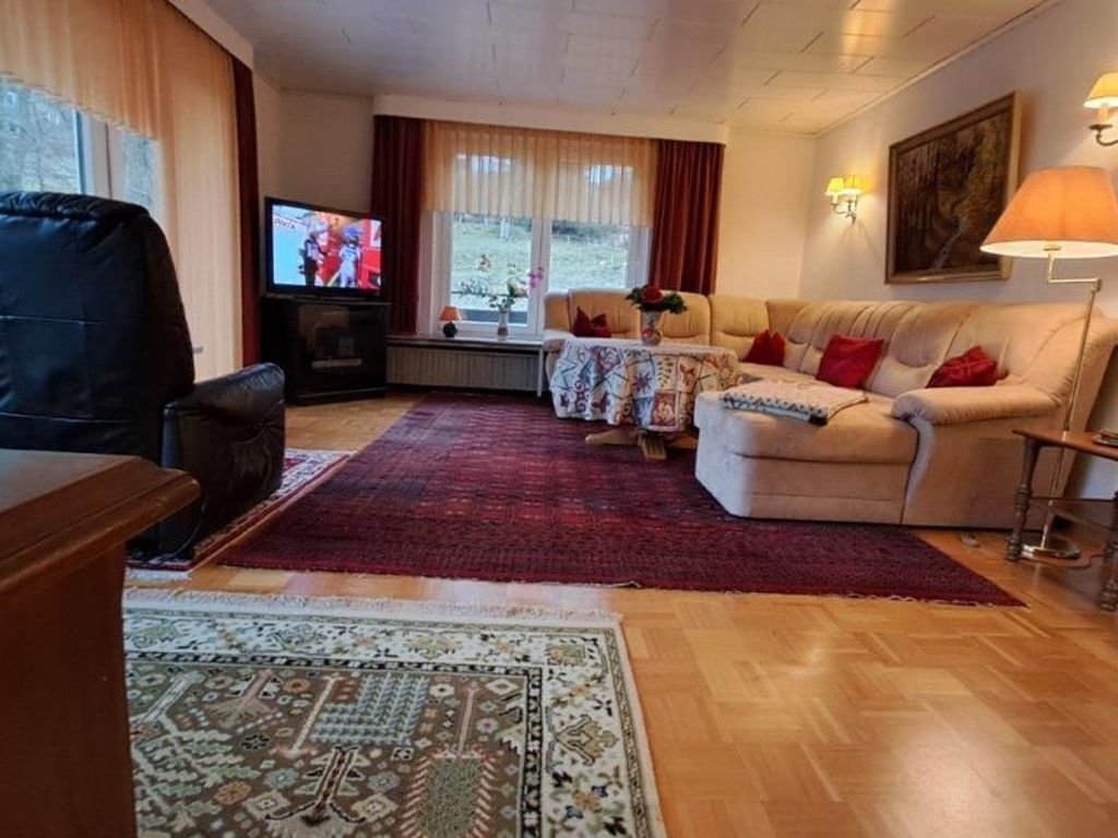 Una sala de estar con sofá, televisor, una mesa de centro y un tapete estampado.