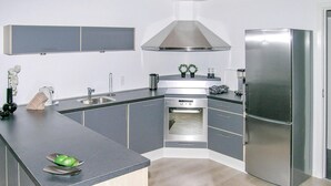 Una cocina moderna con armarios grises, horno empotrado y refrigerador de acero inoxidable.