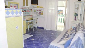 Une pièce comprenant un coin repas, un canapé et une vue sur l’extérieur, visible à travers une porte.