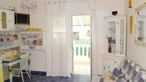 A room with a dining area, a sofa, a cabinet, and a door leading outside. - Holiday apartment near the beach with air conditioning (Baška)