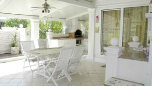 A covered patio with a dining table and chairs, a ceiling fan, and a kitchen area with a grill. - Holiday apartment near the beach with air conditioning (Baška)