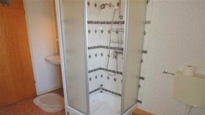 Een badkamer met een douche met glazen wand, een toilet en een wastafel.