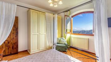 Une chambre à coucher comprenant un lit, une armoire, un radiateur et une fenêtre donnant sur le paysage.