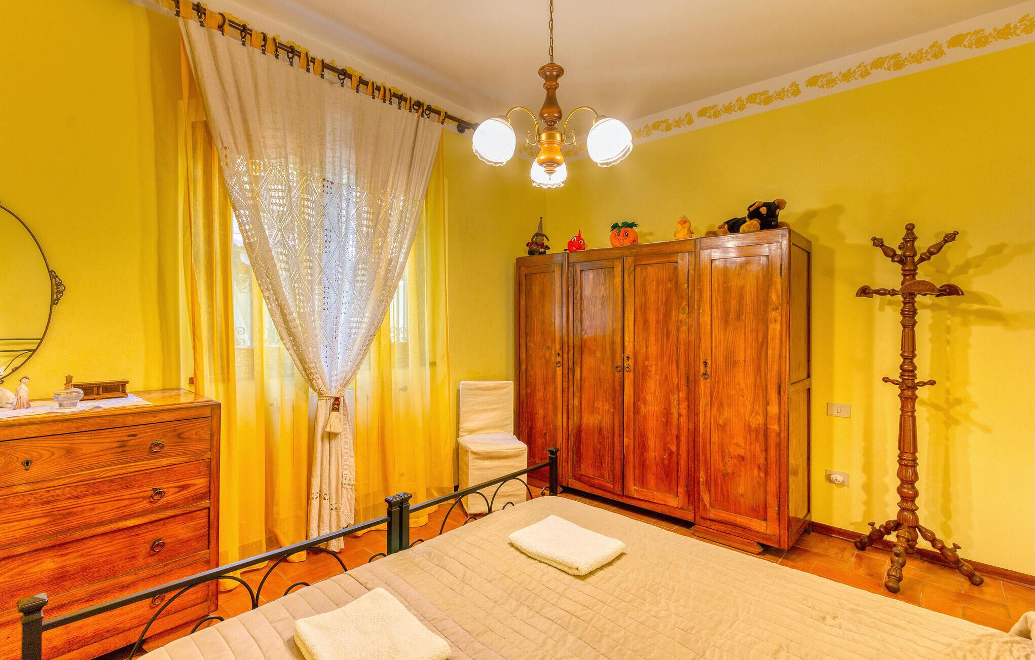 Ein Zimmer mit Bett, Holzschrank und Spiegel.