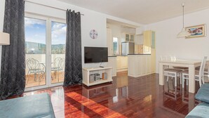 A living room with a TV, sofa, and dining area.