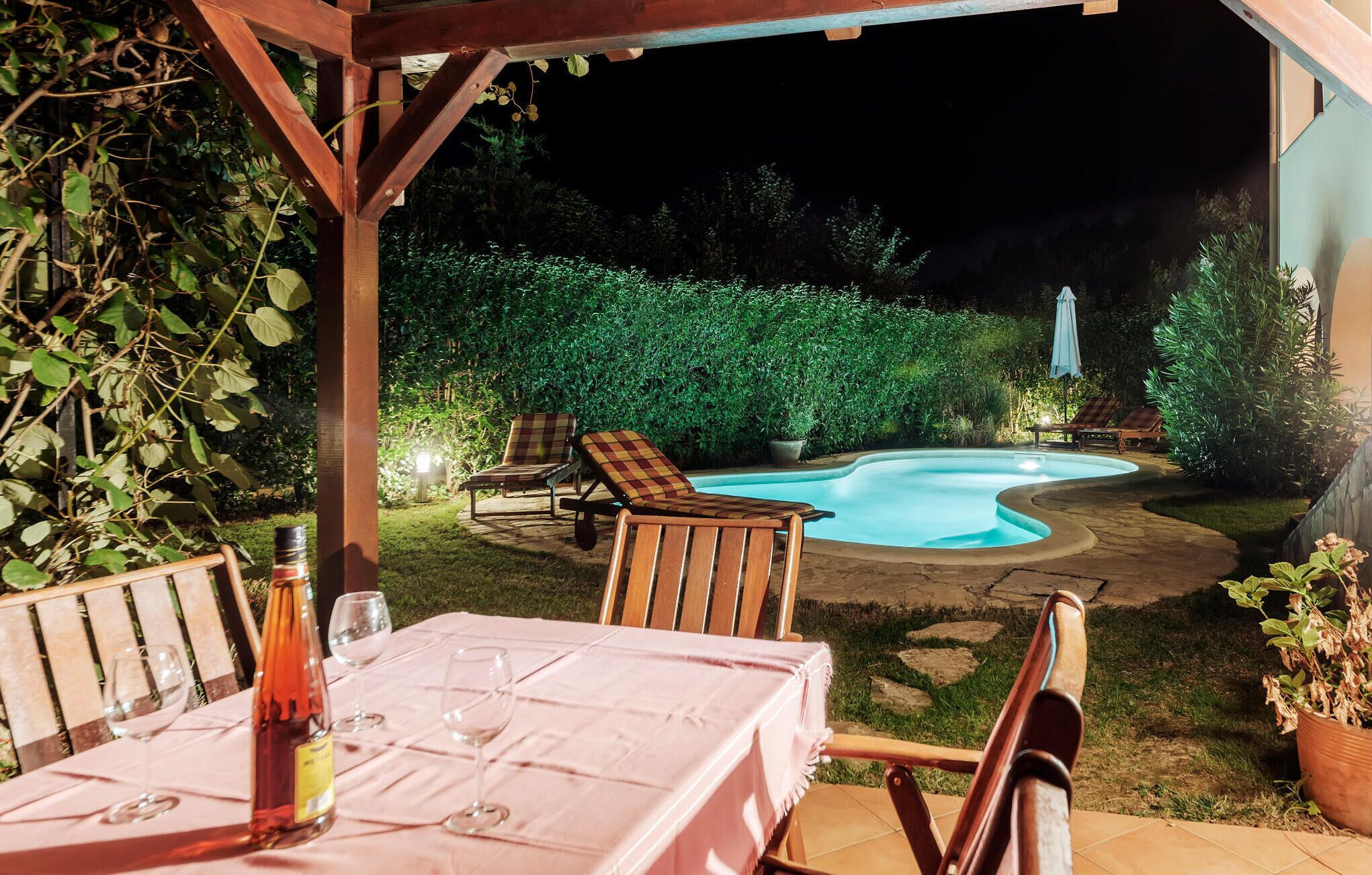 Un patio con piscina, mobiliario exterior y una mesa lista para comer.