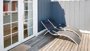 Una terrazza con due lettini, una porta vetrata e un muro blu.