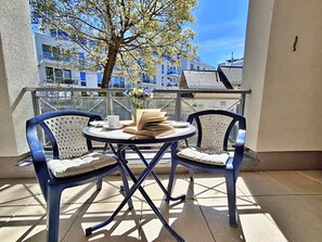 Un balcon avec deux chaises, une table, un livre et une tasse.