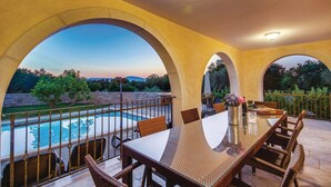 A covered outdoor patio with a pool, dining table, and chairs, surrounded by stone walls and greenery. - Stunning home in Turcic (Turcic)