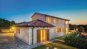 A stone house with a tiled roof, a paved driveway, and a well-maintained lawn. - Stunning home in Turcic (Turcic)