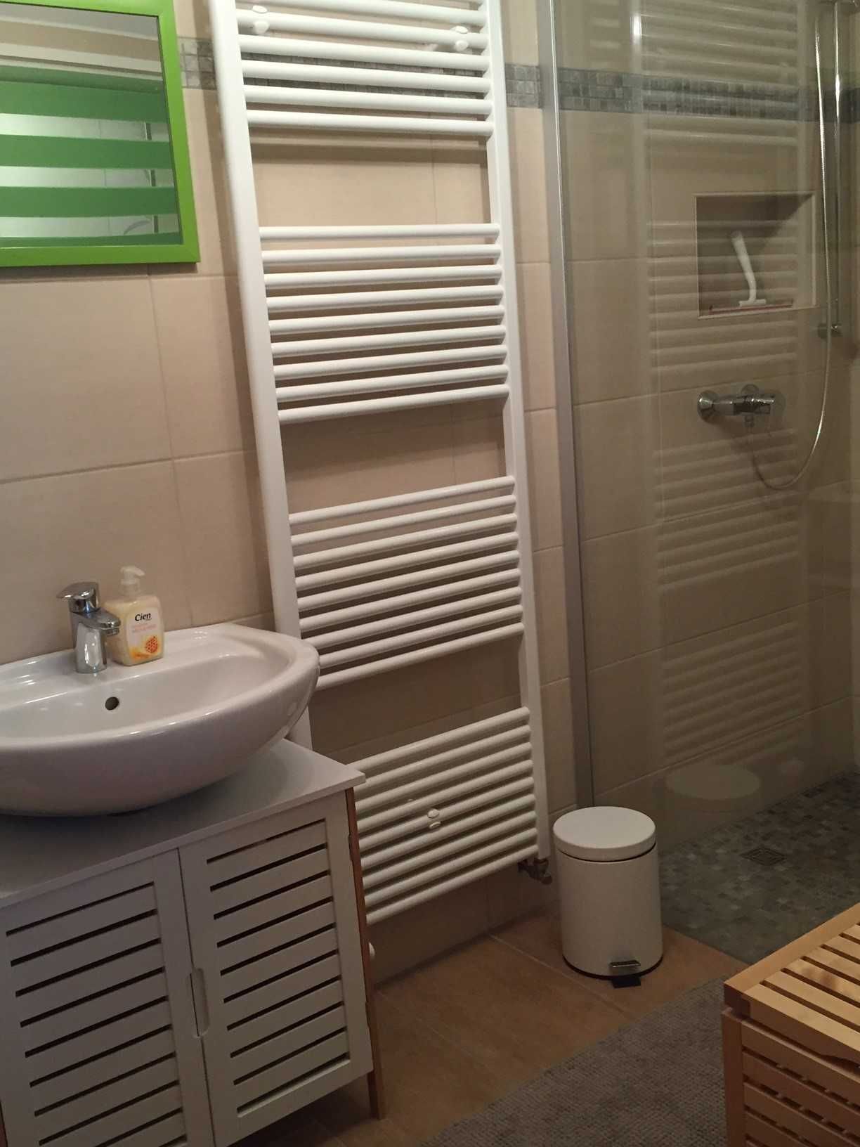 A bathroom with a white sink, a mirror, a towel rack, a toilet, and a shower area.