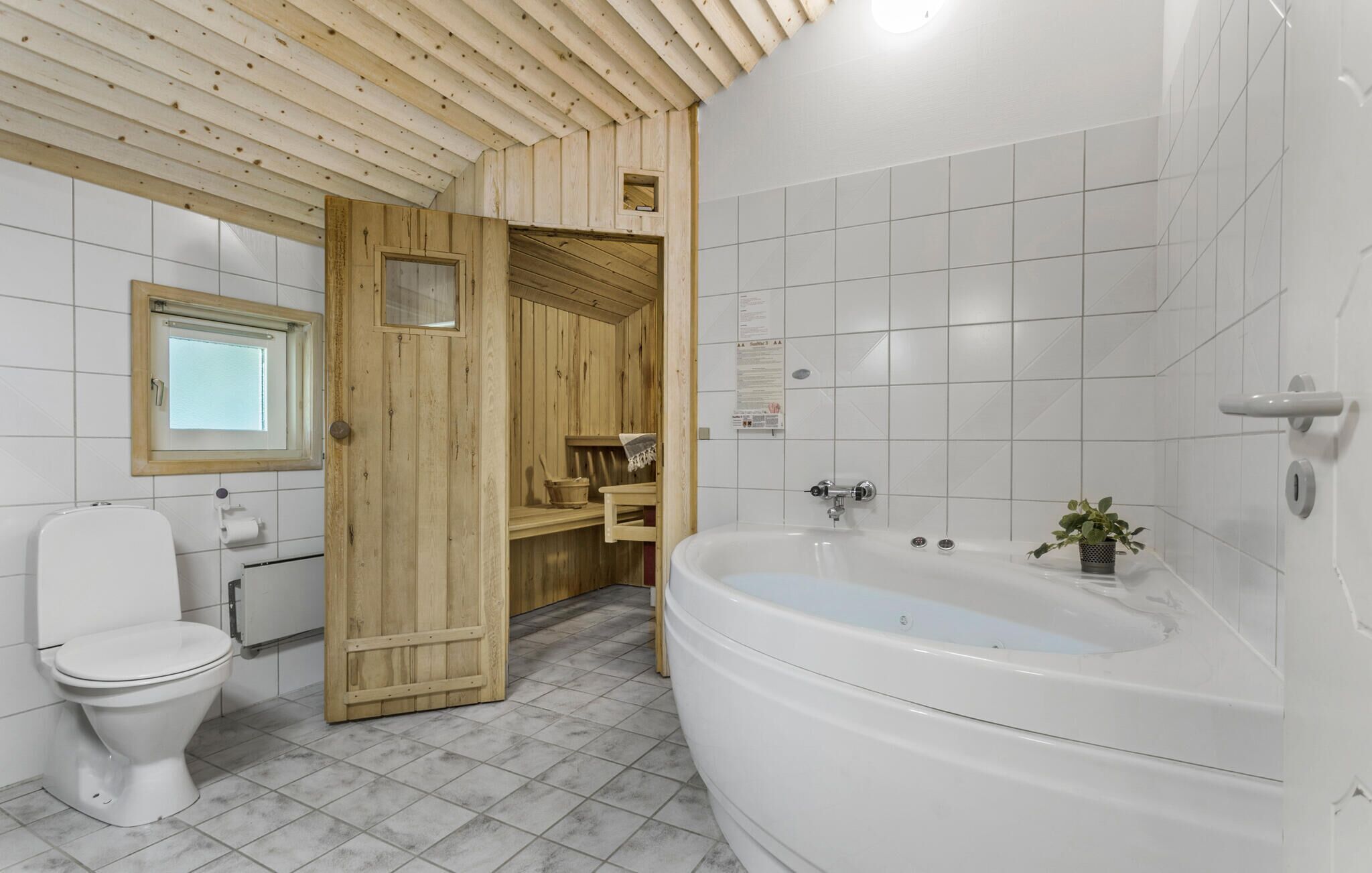 Une salle de bain avec une porte en bois, des toilettes, un lavabo et une baignoire.