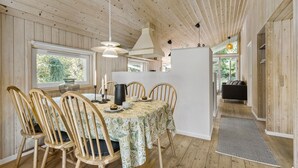 Un intérieur en bois comprenant une table à manger, des chaises et un coin cuisine.