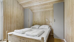 Une chambre avec un lit en bois, un plafond en pente et une armoire.