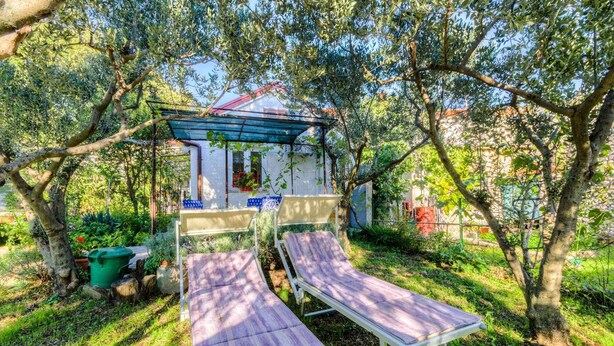 A garden with two sun loungers, a small gazebo, and a green trash bin. - Holiday apartment with a/c (Novi Vinodolski)