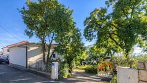 A residential street with a gated entrance, a parked car, and lush greenery. - Holiday apartment with a/c (Novi Vinodolski)