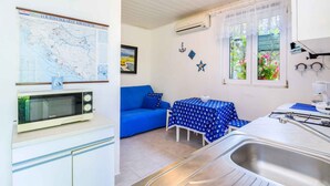 A compact kitchen with a microwave, sink, and a dining area with a table and blue tablecloth. - Holiday apartment with a/c (Novi Vinodolski)