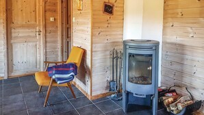 Un intérieur en bois avec un poêle à bois, un fauteuil avec une couverture et une porte.