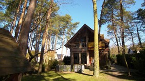 A wooden cabin surrounded by tall trees, with a clear sky above. - Apartment 01 - Holiday home Knopf with 3 apartments, incl. WLAN (Zinnowitz)