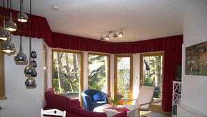 A cozy living room with a dining area, large windows, and a view of trees. - Apartment 01 - Holiday home Knopf with 3 apartments, incl. WLAN (Zinnowitz)