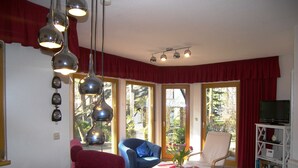 A dining area with a table, chairs, and a TV stand with books. - Apartment 01 - Holiday home Knopf with 3 apartments, incl. WLAN (Zinnowitz)