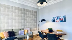 Ein modernes Wohnzimmer mit grauem Sofa, Holztisch und Esstisch mit Stühlen.