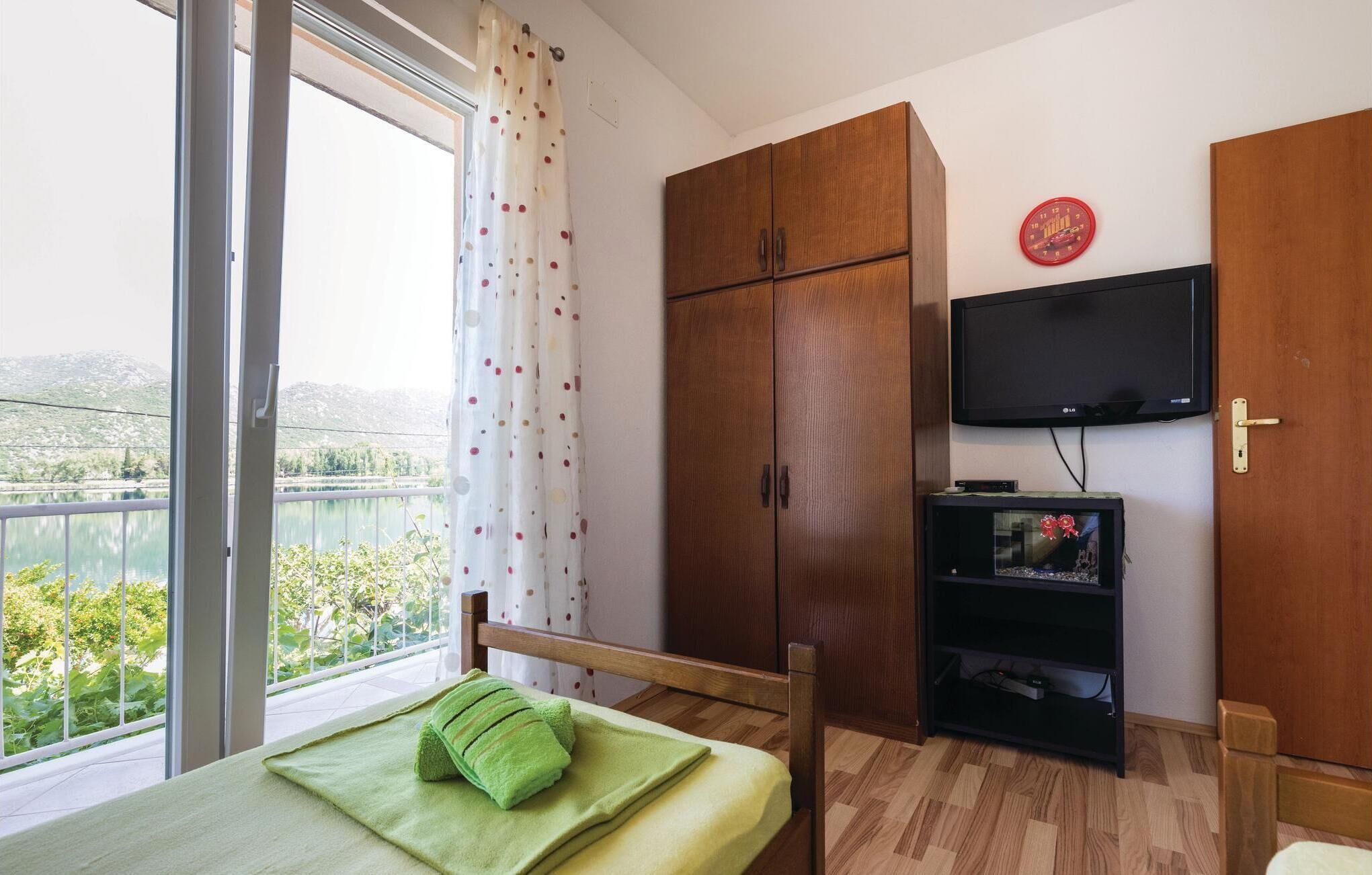 Une chambre avec un lit, une télévision, une armoire et une vue sur un lac.