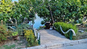 A pathway leading to a gazebo with a swan statue, surrounded by lush greenery and a body of water. - Amazing apartment in Bacinska jezera (Bacinska jezera)