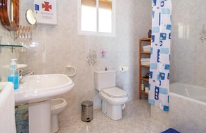 A bathroom with a sink, toilet, and bathtub. There is a sign above the toilet and a shower curtain with a pattern. - 3 bedroom cozy home in Torrox (Torrox)