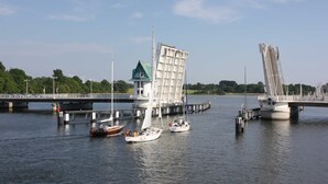 Une rivière avec des bateaux, un pont et un bâtiment surmonté d’un toit végétalisé.