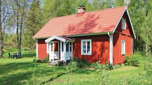 A red wooden house with a white porch and a red roof, surrounded by greenery. - 3 bedroom stunning home in Häradsbäck (Häradsbäck)