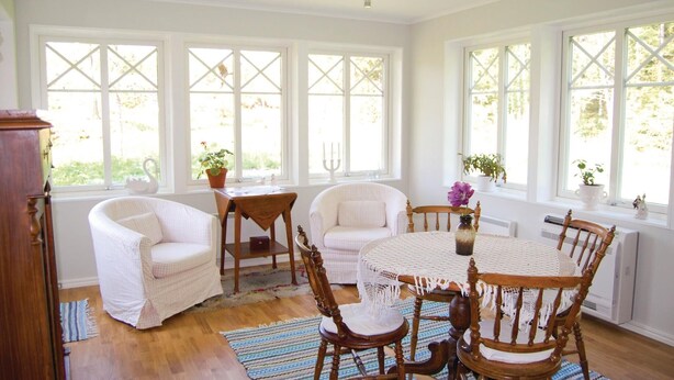 A bright room with large windows, a round wooden table, and two white armchairs. - 3 bedroom stunning home in Häradsbäck (Häradsbäck)
