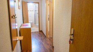 A narrow hallway with wooden flooring and doors leading to a bathroom and another room. - Triple room (17) - Pension Zur Kurve (Prohn)