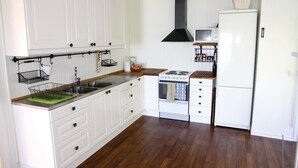 A compact kitchen with white cabinetry, a stove, microwave, and a refrigerator.