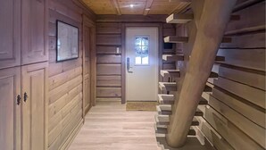 A wooden interior with a staircase leading to a door with a window.