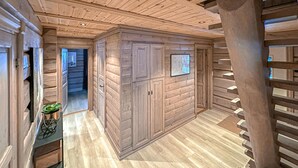 A wooden interior with a high ceiling, built-in cabinets, and a staircase.