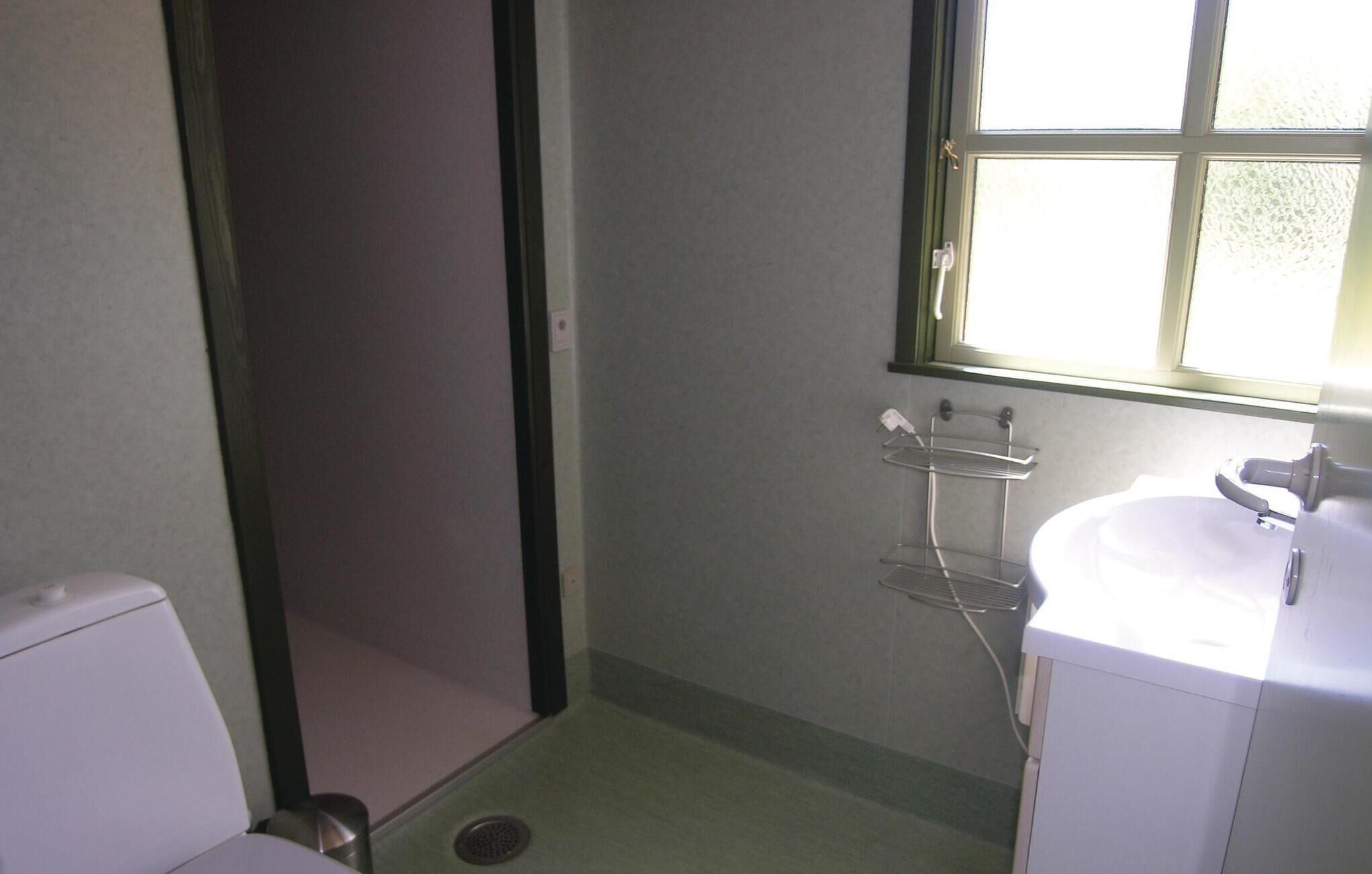 Un baño pequeño con inodoro, lavamanos, ventana y ducha.