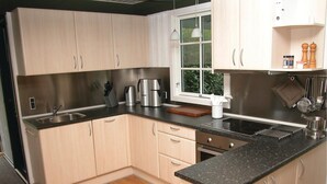 Une cuisine moderne avec des meubles de couleur bois clair, un évier en acier inoxydable et un plan de travail noir.
