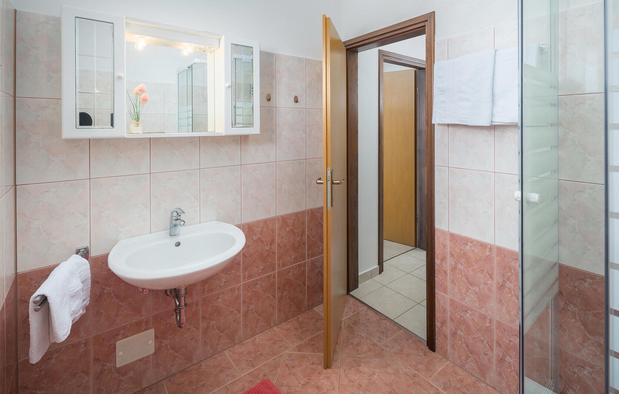 A bathroom with a sink, mirror, and shower area.