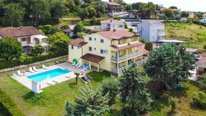 A multi-story building with a swimming pool, surrounded by greenery and other residential structures. - Gorgeous apartment in Porec with swimming pool (Porec)