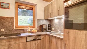 Una cucina con mobili in legno, forno integrato, macchina da caffè e una finestra vista paesaggio.