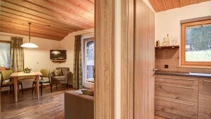 Un ambiente accogliente con pavimento in legno, una zona pranzo con tavolo e sedie, un divano, una TV montata a parete e una finestra con vista sull'esterno.