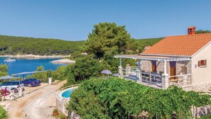 A villa with a pool, a view of the sea, and a car parked in front.