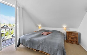Un dormitorio con cama, mesitas de noche y vistas al exterior.