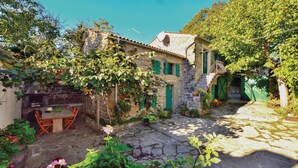 A stone house with a stone patio, a table, and chairs.