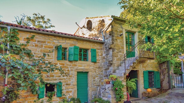 A stone building with green shutters and a small balcony.